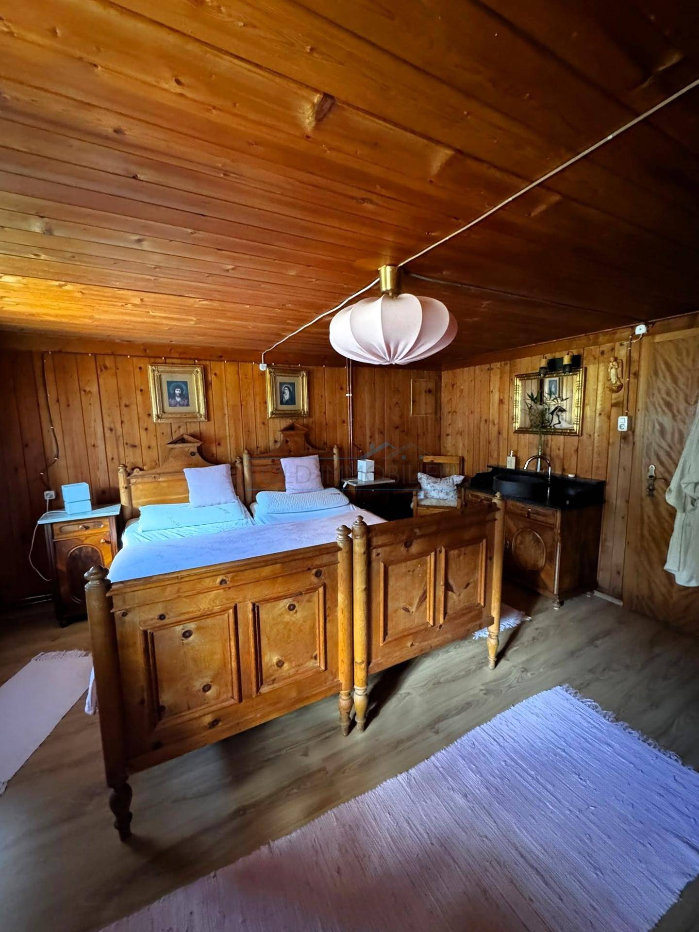 Schlafzimmer im Landhausstil mit zwei Einzelbetten, Holztäfelung und integriertem Waschbecken.