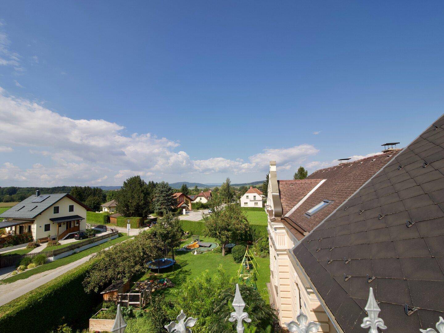 Weitläufiger Blick über die ländliche Umgebung mit Häusern, Bäumen und Spielplatz.