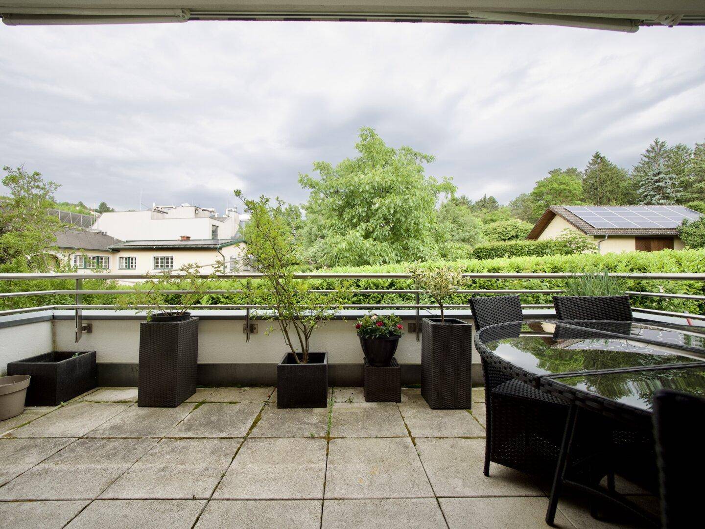 Große Terrasse mit Pflanzen und Blick ins Grüne sowie auf umliegende Gebäude.