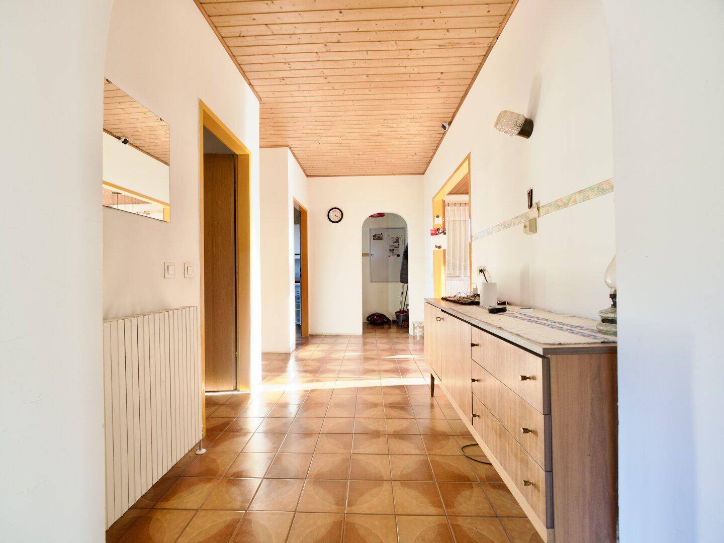 Heller Flur mit gemusterten Fliesen und Holzdecke, der zu weiteren Räumen führt.