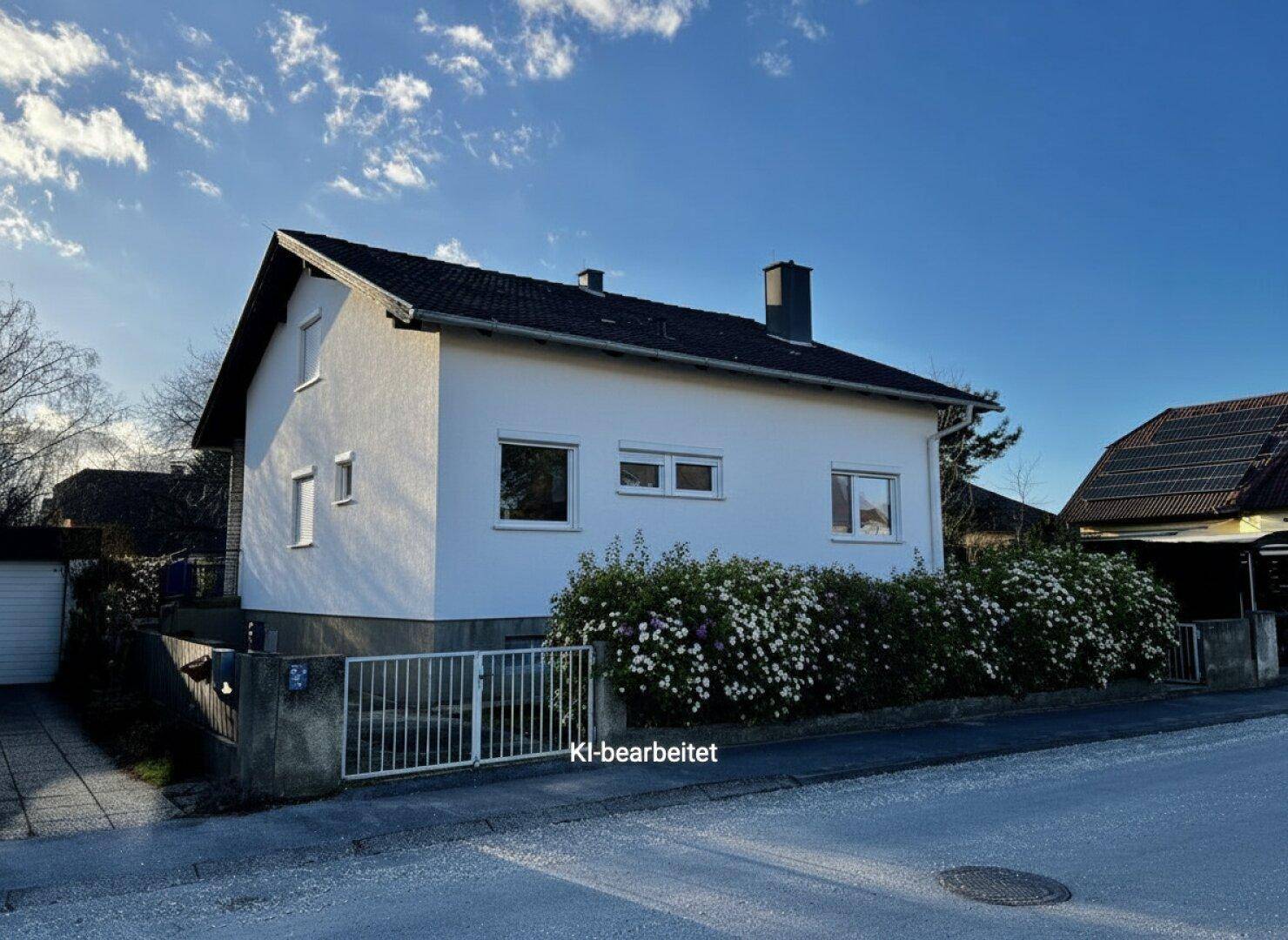 Einfamilienhaus mit gepflegter Fassade und blühenden Sträuchern im Vorgarten.