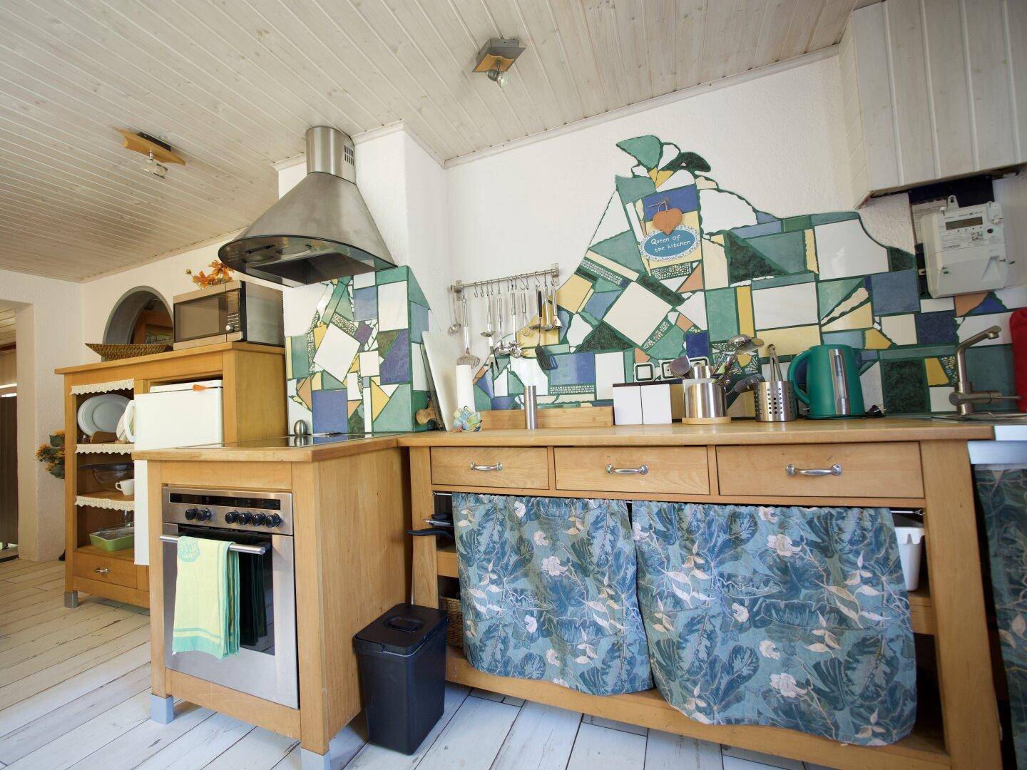 Eine traditionelle Holzküche mit bunten Fliesen an der Wand und integriertem Backofen.