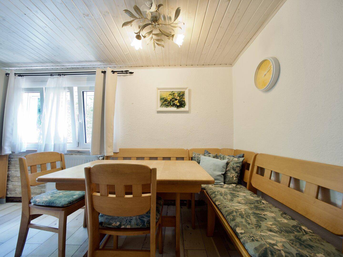 Ein gemütlicher Essbereich mit Holztisch, Eckbank und Stühlen unter einer Holzdecke.