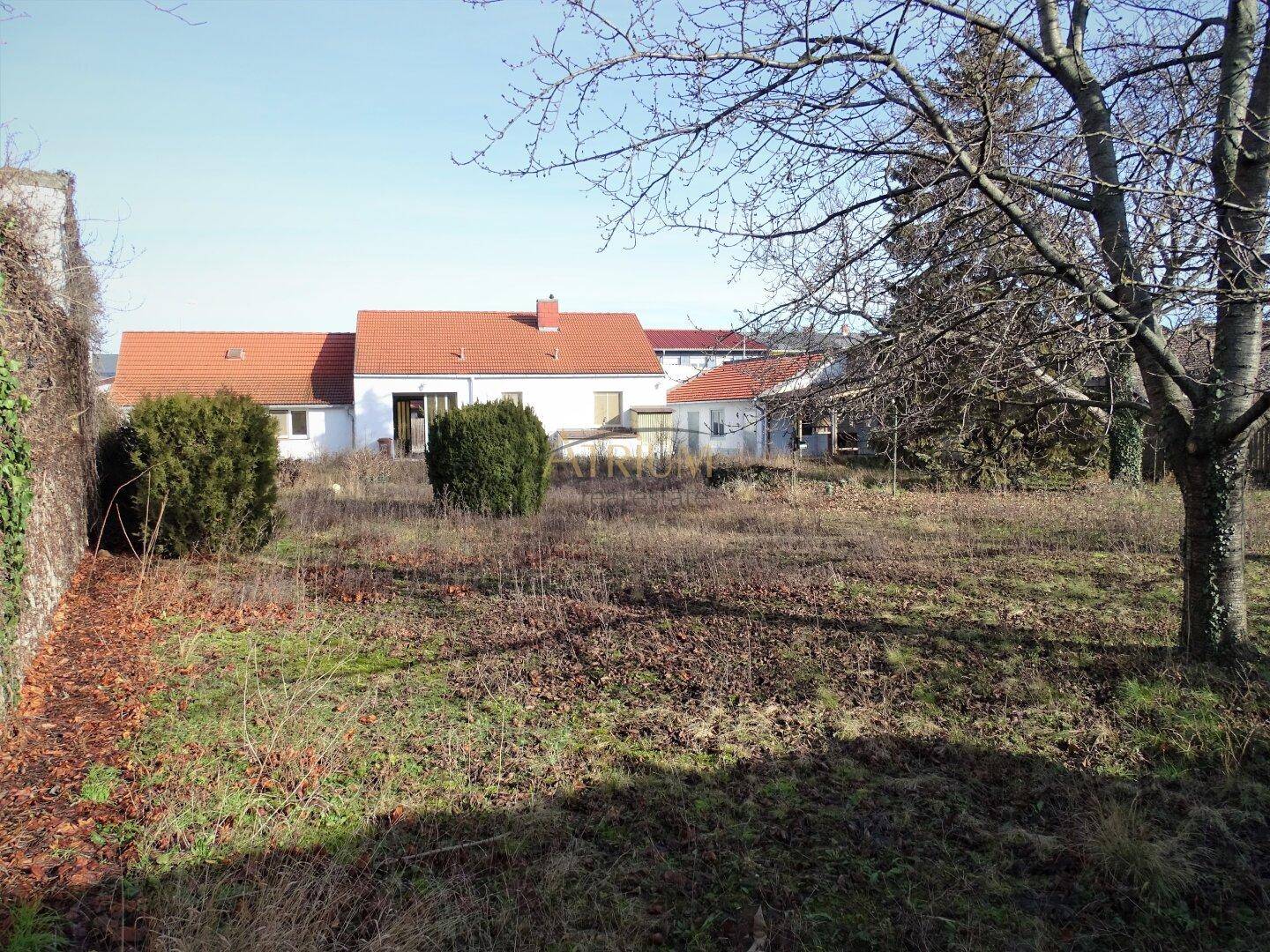 Rückansicht eines Hauses mit rotem Ziegeldach und einem großen, sonnigen Grundstück.