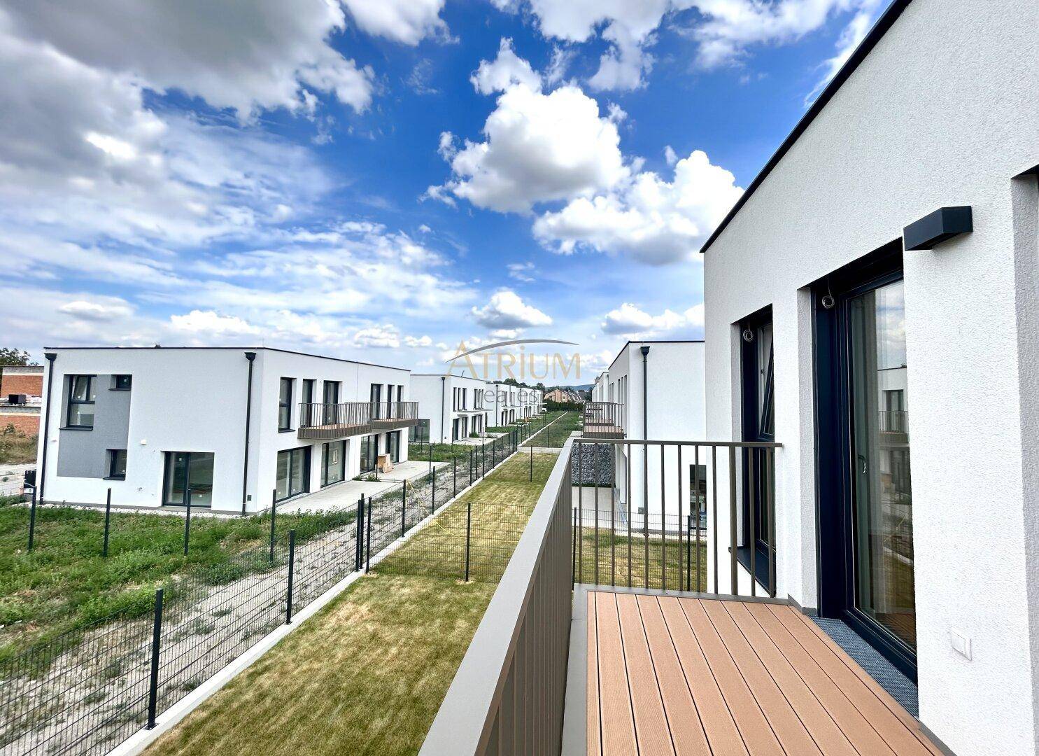 Balkon mit Holzboden und weitem Blick über die Reihenhäuser und Gärten.