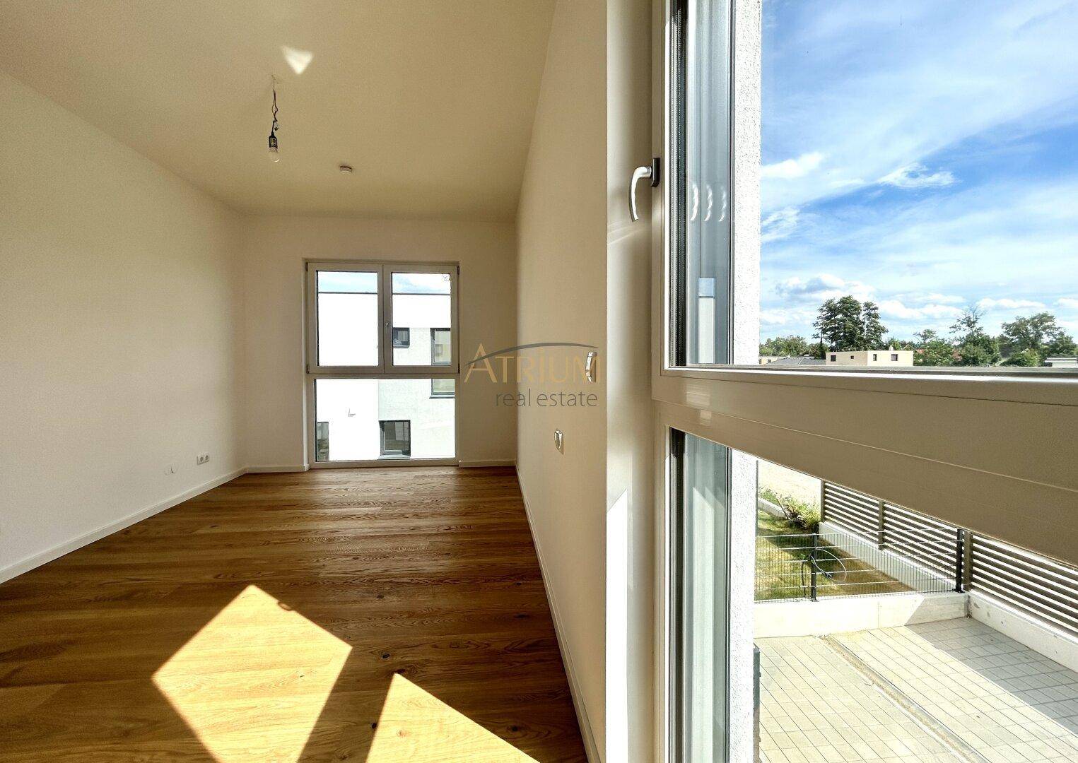 Helles Zimmer mit Holzboden und großen Fenstern, inklusive französischem Balkon.