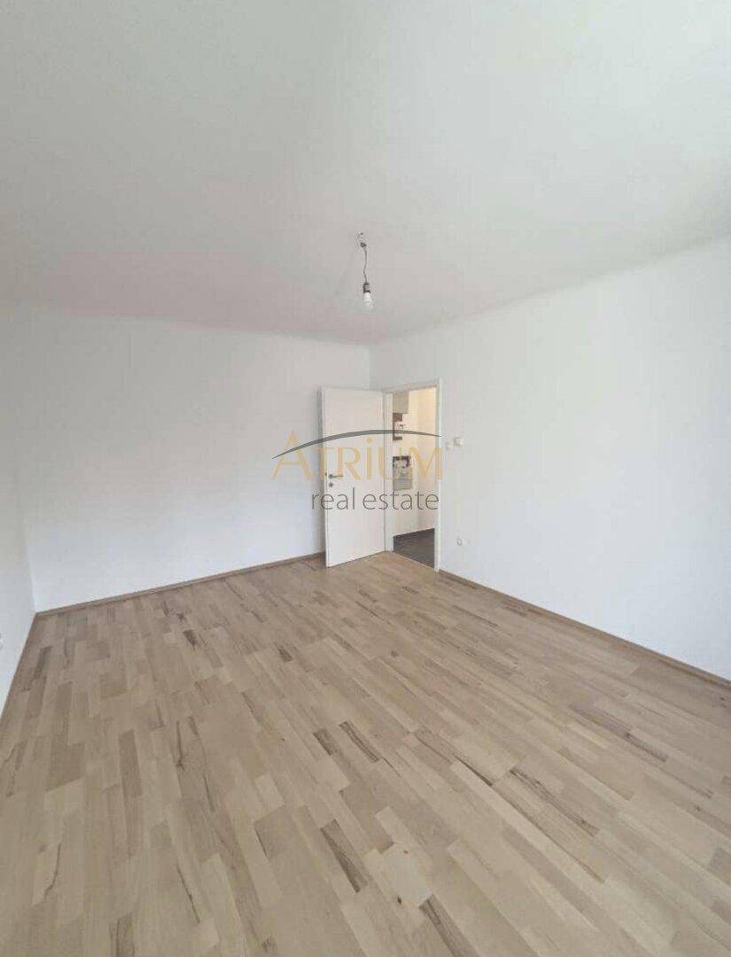 Leeres Zimmer mit Parkettboden und weiß gestrichenen Wänden, bereit zur individuellen Gestaltung.