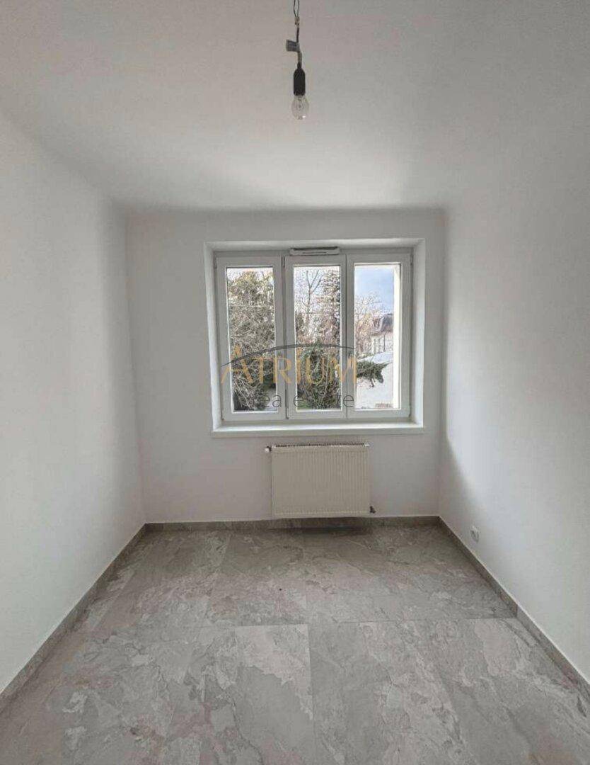 Kleineres Zimmer mit grauen Fliesen und Fenster, geeignet als Schlaf- oder Arbeitszimmer.