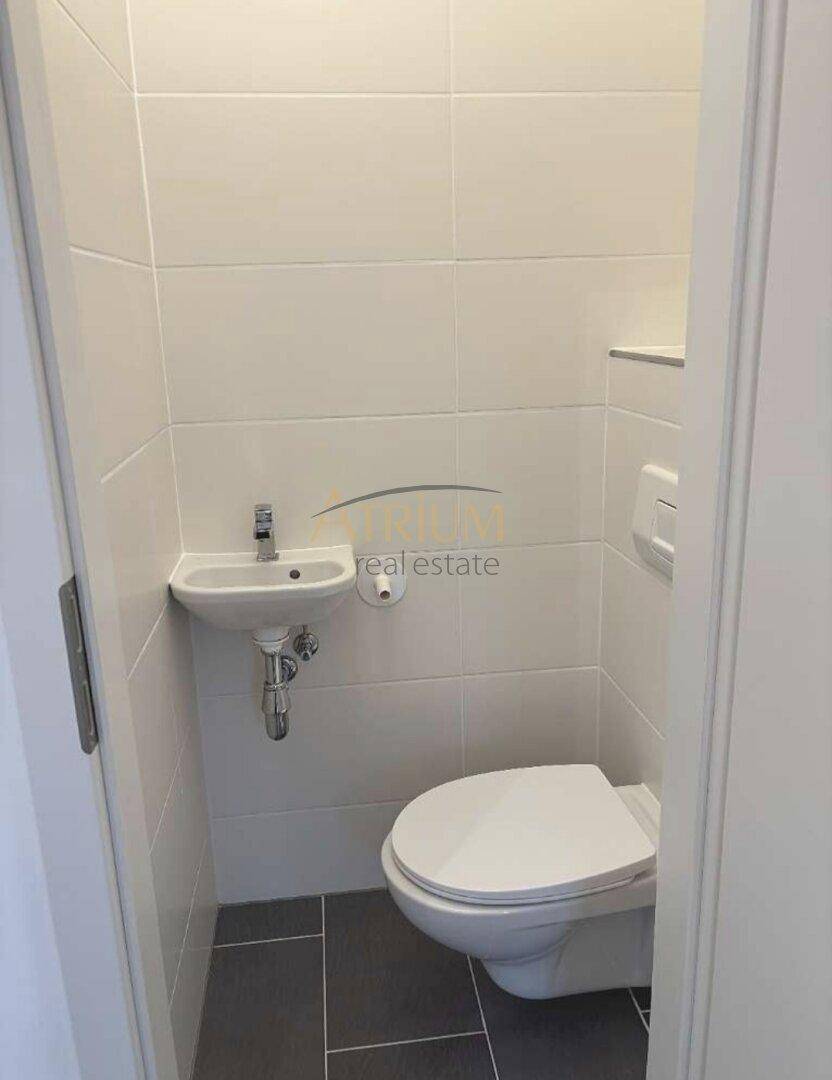Separates Gäste-WC mit wandhängender Toilette und kleinem Handwaschbecken.
