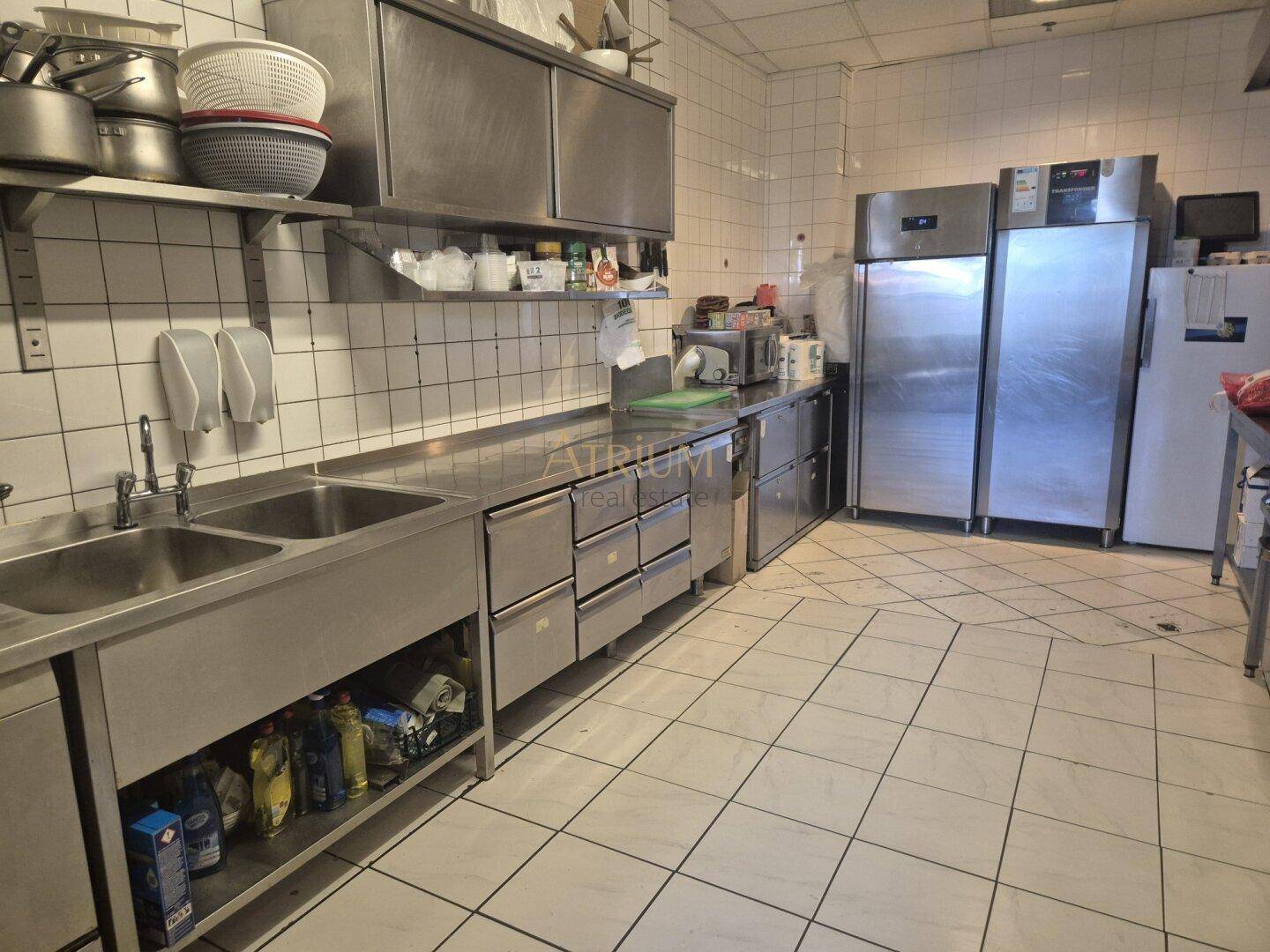 Professionelle Großküche mit Edelstahlspülen, Arbeitsflächen und großen Kühlschränken.