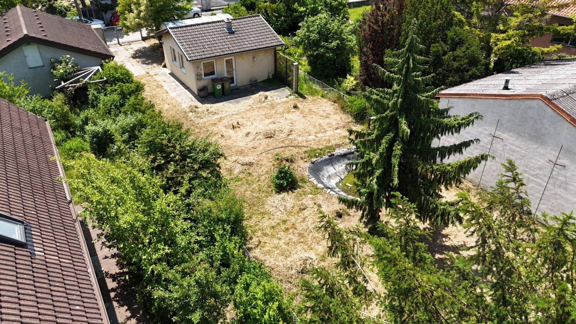 Luftaufnahme des Grundstücks mit kleinem Haus, Teich und umliegender grüner Landschaft.