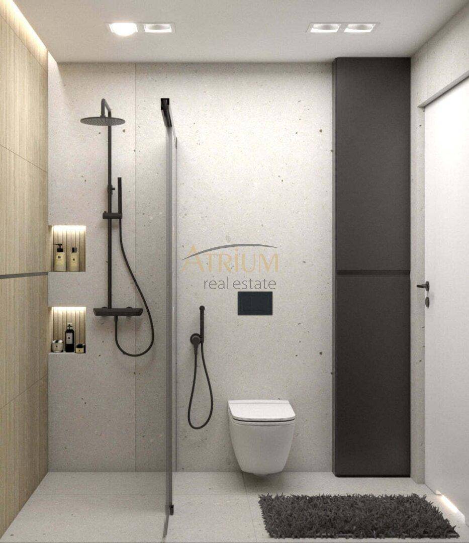 Modernes Badezimmer mit ebenerdiger Dusche, wandhängendem WC und grauen Fliesen.