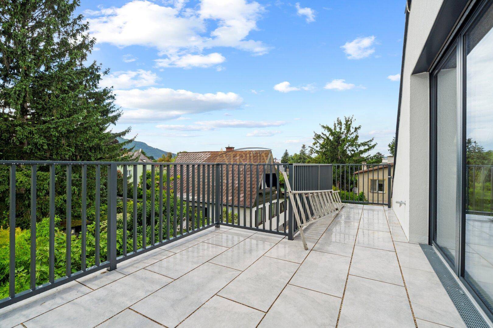 Geräumige, geflieste Terrasse mit Metallgeländer und weitem Blick ins Grüne.