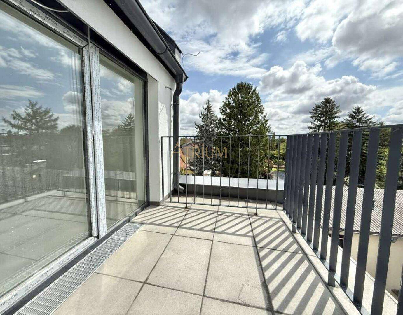 Heller Balkon mit Fliesenboden, moderner Brüstung und Blick ins Grüne.