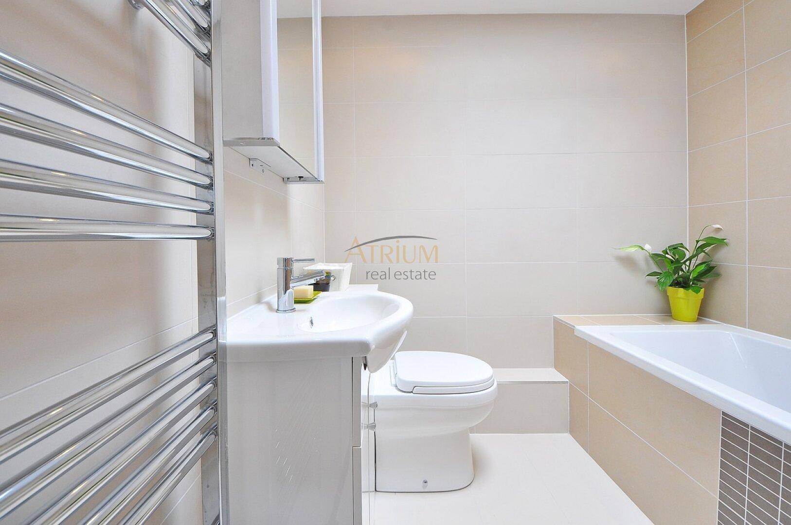 Modernes Badezimmer mit Badewanne, Waschbecken, Toilette und beheiztem Handtuchhalter.