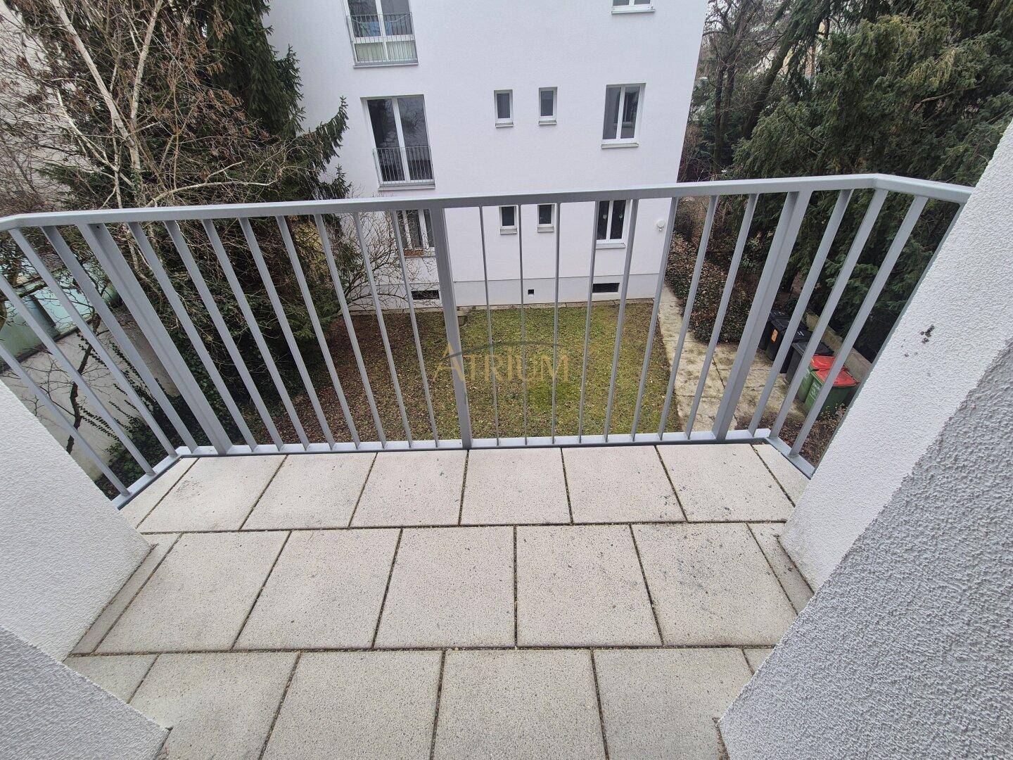 Balkon mit Fliesenboden und Metallgeländer, bietet einen Blick auf den Gartenbereich.
