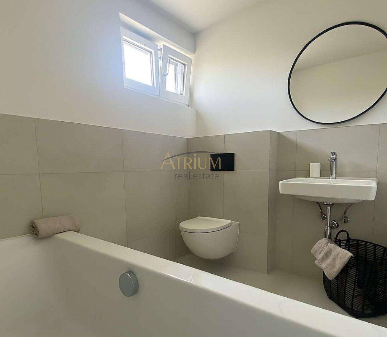 Helles Badezimmer mit Badewanne, Waschbecken und Fenster für natürliches Licht.