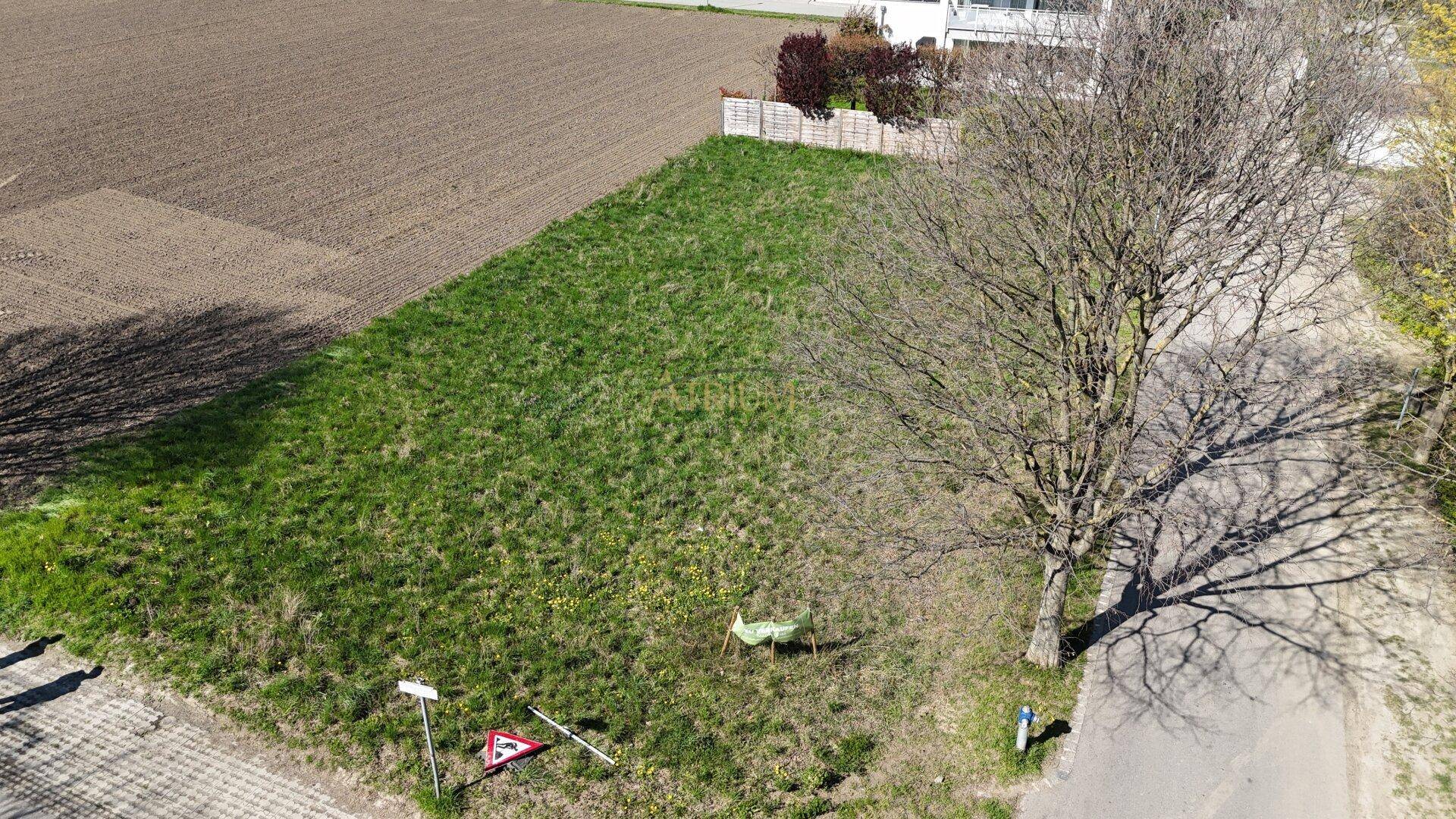 Übersicht des unbebauten Grundstücks aus der Vogelperspektive mit angrenzendem Feld und Straße.