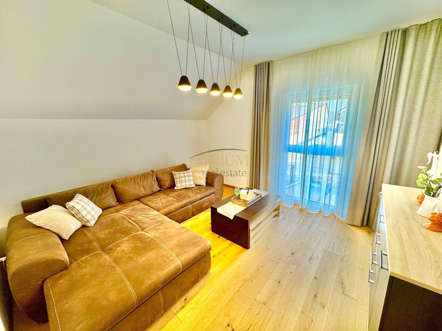Helles Wohnzimmer im Dachgeschoss mit großem Ecksofa und Holzboden.