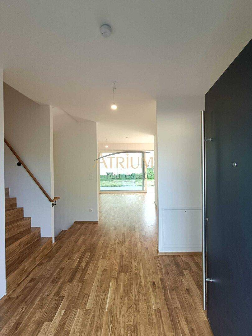 Geräumiger Eingangsbereich mit Holztreppe und hellem Parkettboden, führt in den Wohnbereich.