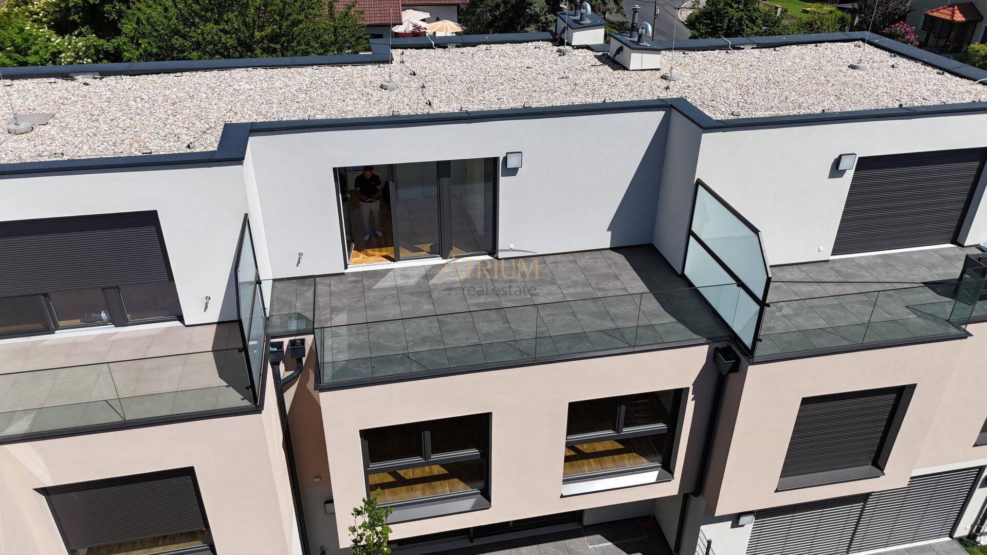 Geräumige Terrasse mit modernen Fliesen und Glasgeländer, zugänglich von den Innenräumen.