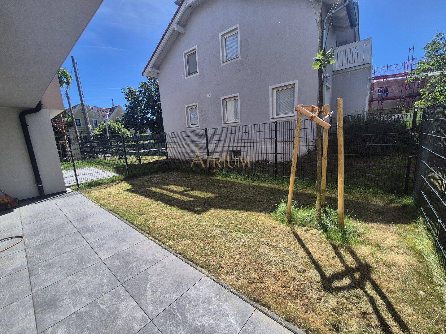 Kleiner privater Gartenbereich mit Rasenfläche und gepflasterter Terrasse neben dem Haus.