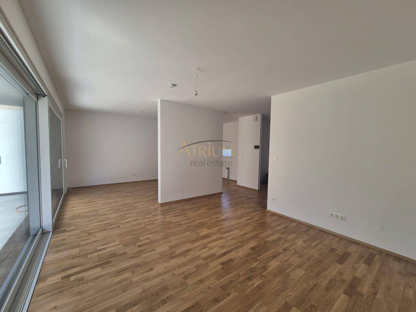 Heller Wohnbereich mit Parkettboden und Zugang zu einer großen Terrasse, ideal für offenes Wohnen.