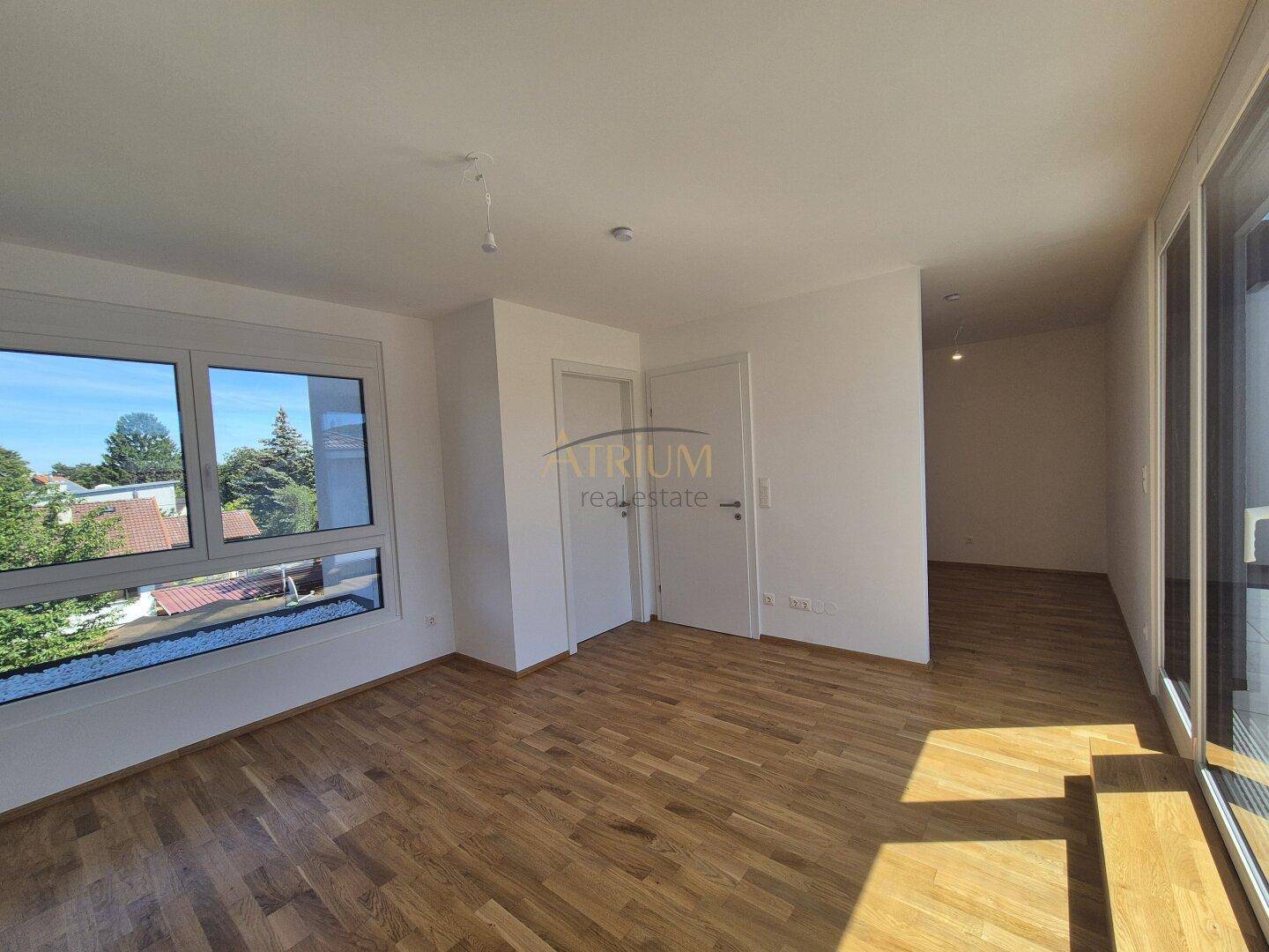 Helles Schlafzimmer mit Eichenparkett und großen Fenstern, die einen grünen Ausblick bieten.