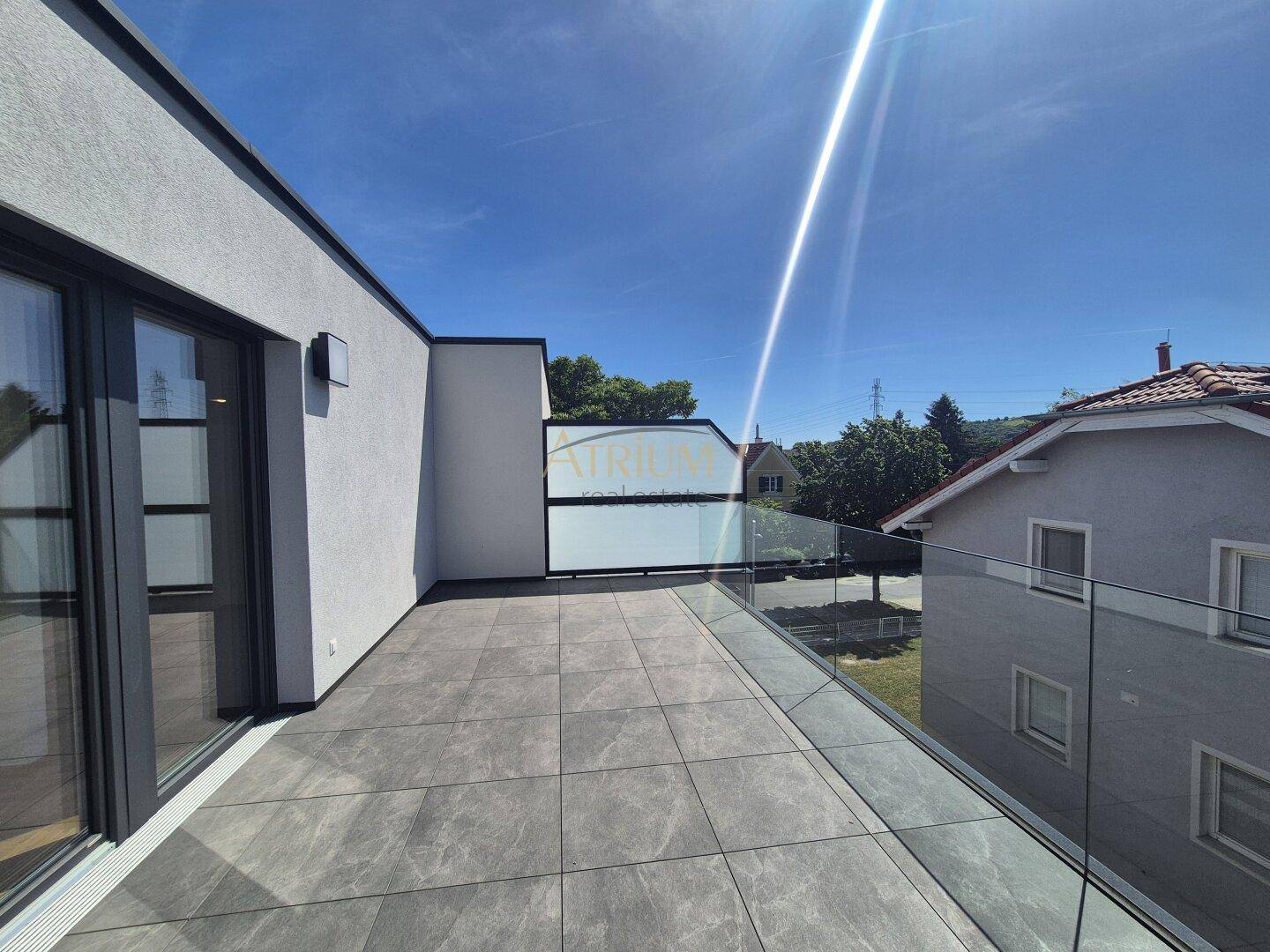 Geräumige Sonnenterrasse mit modernen Fliesen und Glasgeländer, ideal zum Entspannen im Freien.