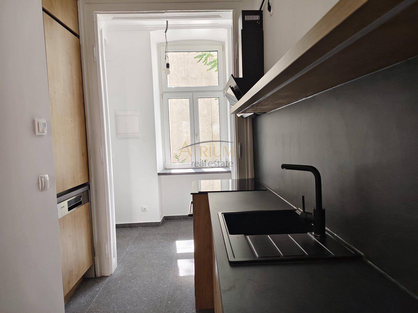 Detailansicht der modernen Küche mit Spüle, dunkler Arbeitsplatte und Fensterblick.