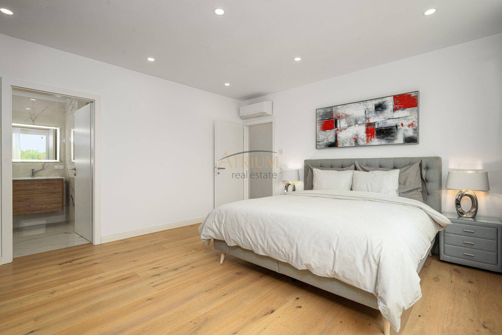 Geräumiges Schlafzimmer mit großem Bett, moderner Kunst und direktem Zugang zum Badezimmer.