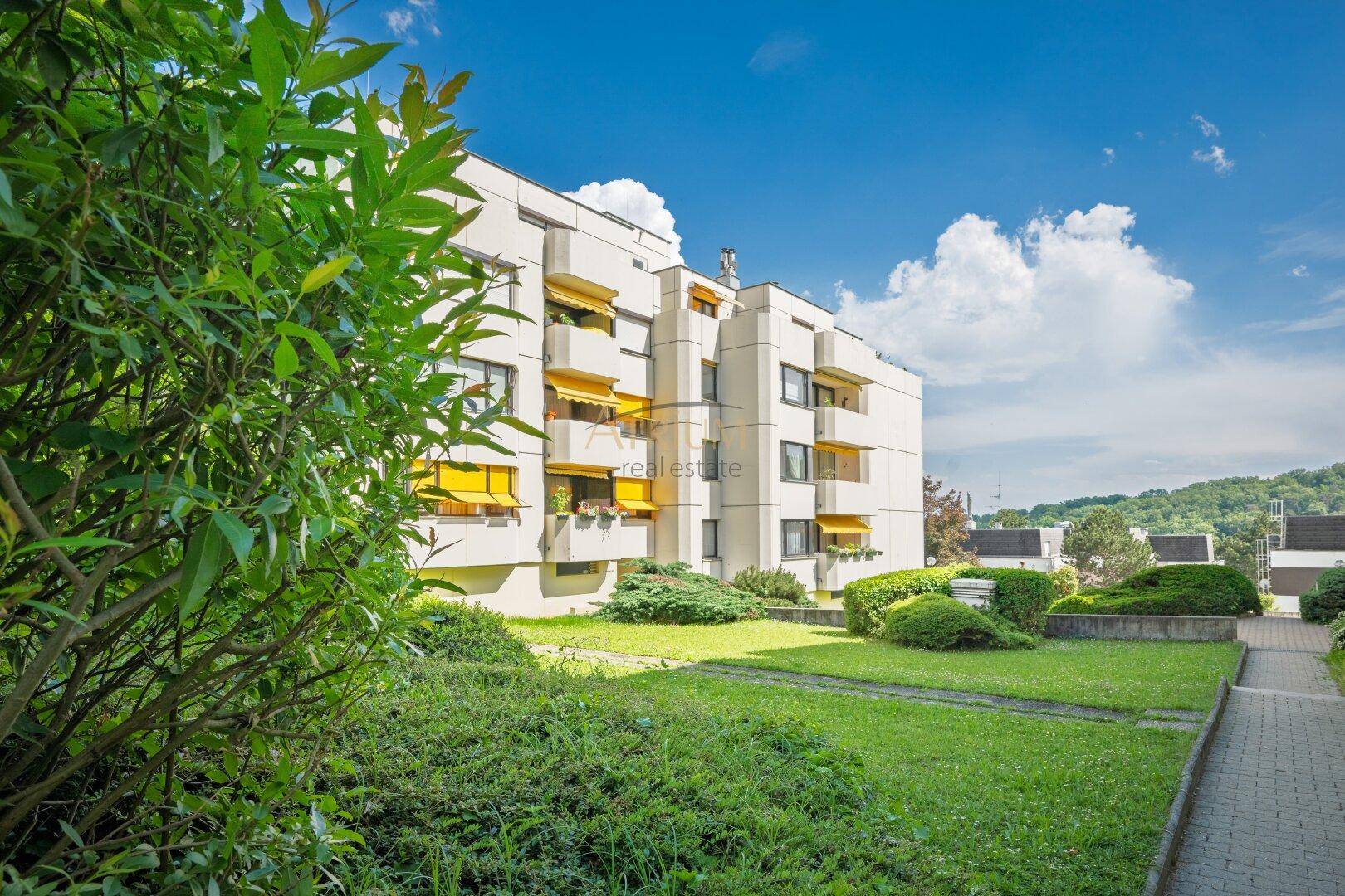 Modernes Apartmentgebäude mit Balkonen, umgeben von gepflegten Grünflächen.