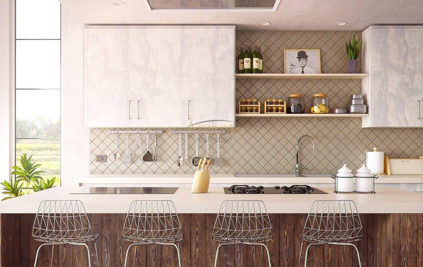 Moderne Küche mit Frühstücksbar, hellen Schränken und gemusterten Fliesen an der Wand.