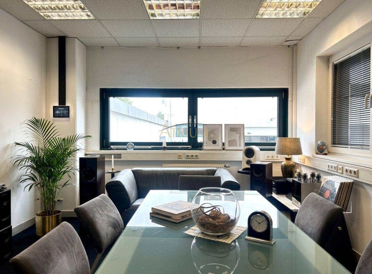 Modern eingerichtetes Büro mit großem Tisch, bequemen Stühlen und Blick nach draußen.