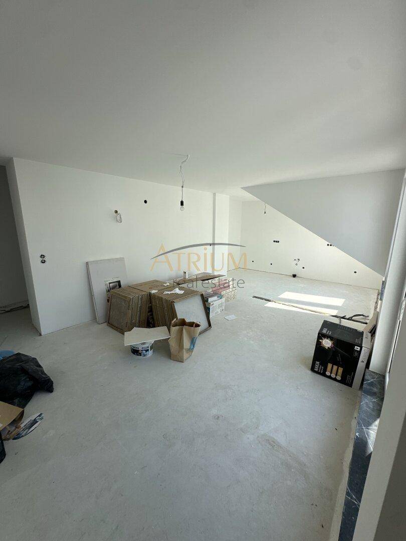 Großer, unfertiger Raum mit Dachschräge und viel Tageslicht, bereit für den Ausbau.
