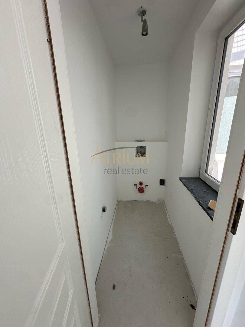 Kleiner, unfertiger Raum, wahrscheinlich eine Gästetoilette, mit Fenster und Anschlüssen.