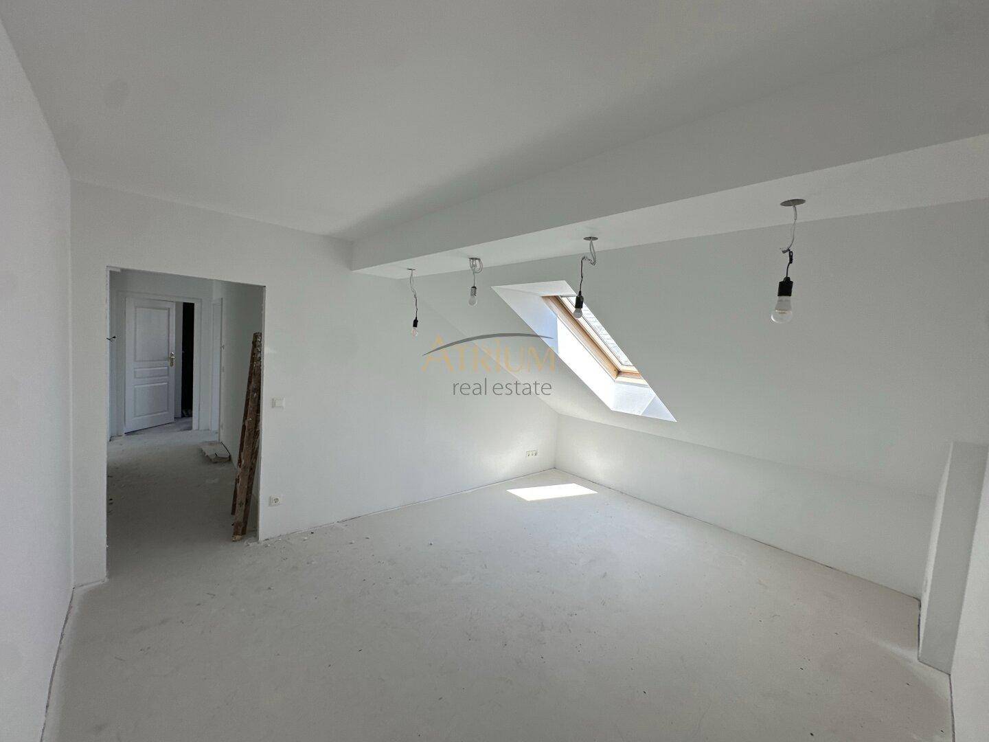 Unfertiger Raum mit Dachschräge und Dachfenster, bereit für die weitere Gestaltung.