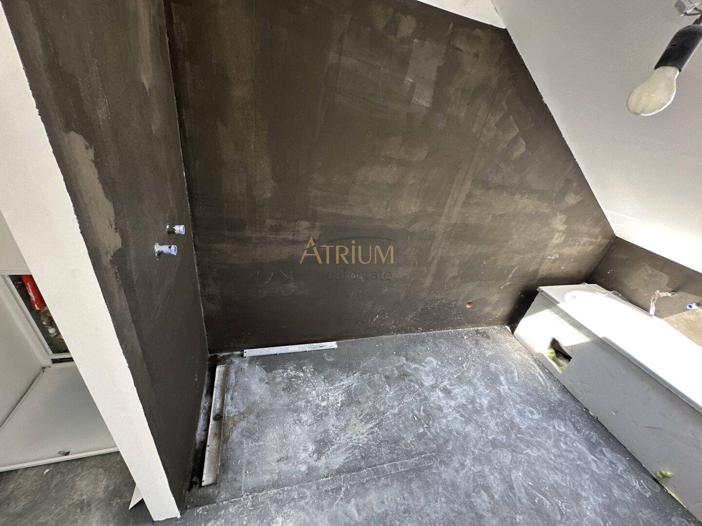 Unfertiges Badezimmer mit vorbereiteten Wänden und einer Badewanne unter der Dachschräge.