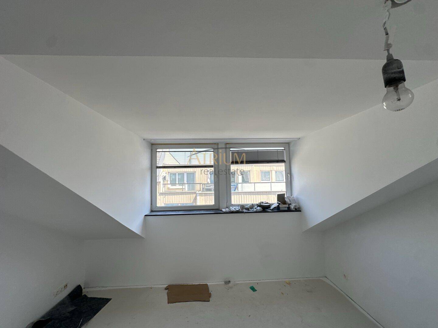 Unfertiger Raum mit Fenster und Dachschrägen, bereit für die weitere Gestaltung.