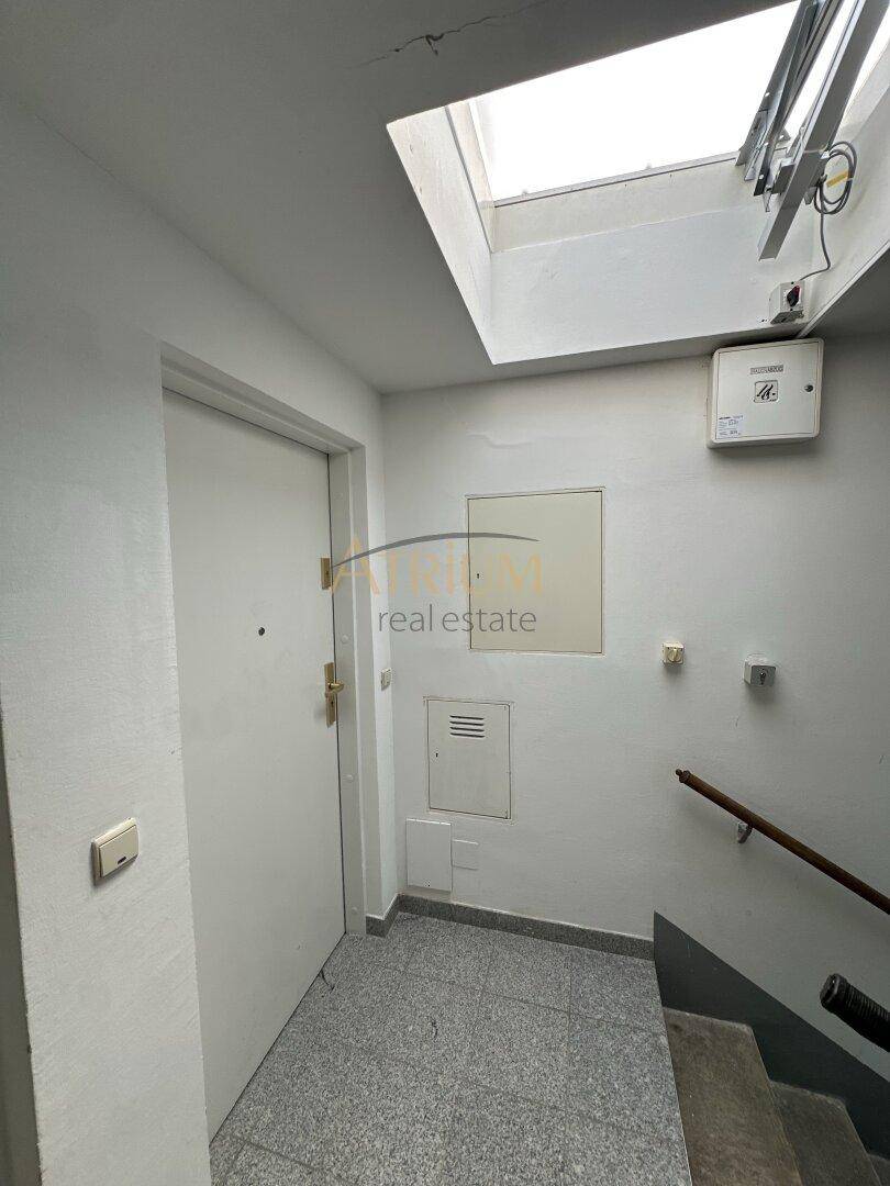 Eingangsbereich mit Treppe, Fliesenboden und einem Dachfenster, das Tageslicht spendet.
