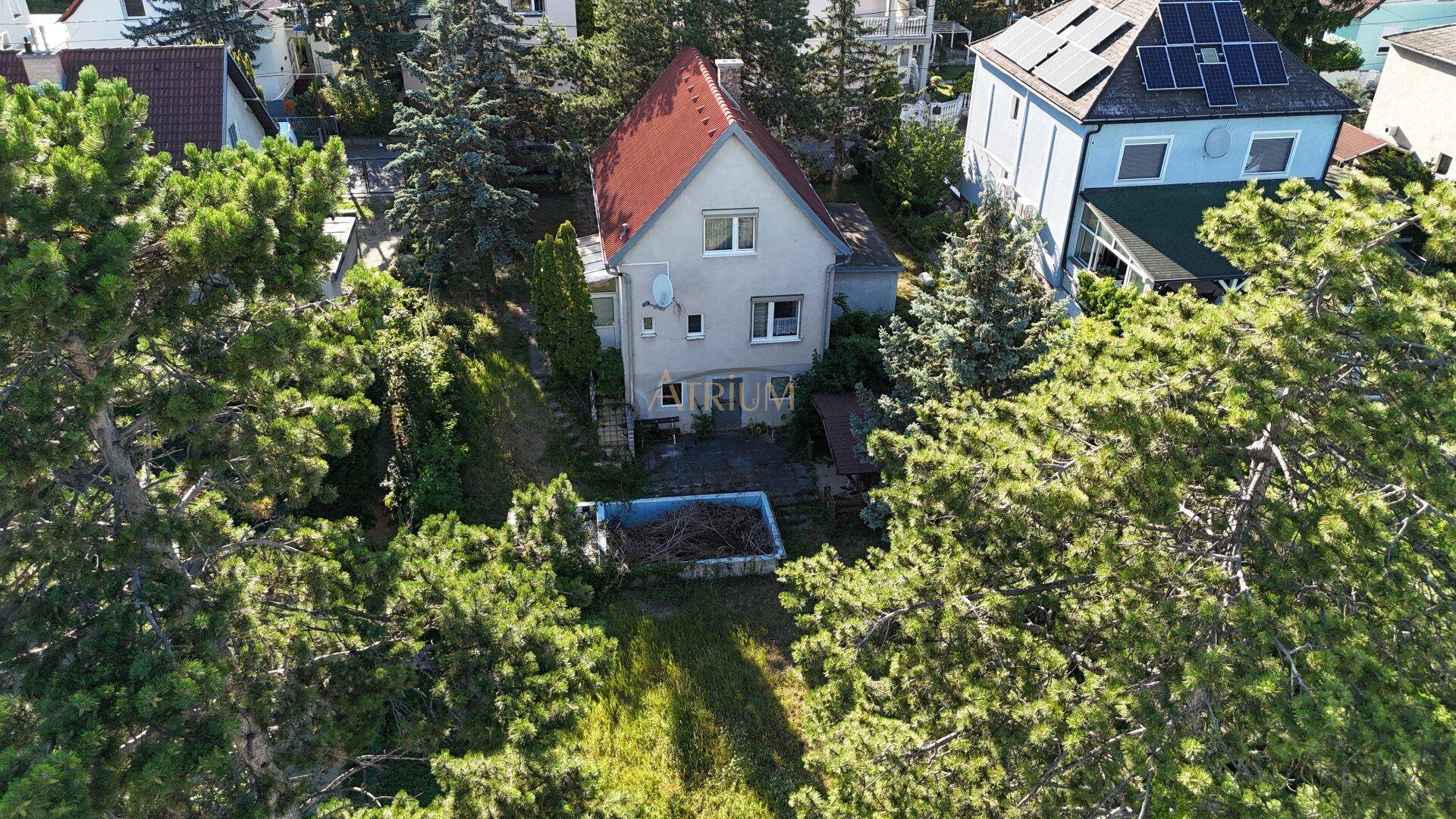 Luftaufnahme eines Einfamilienhauses mit Garten und umliegender grüner Landschaft.