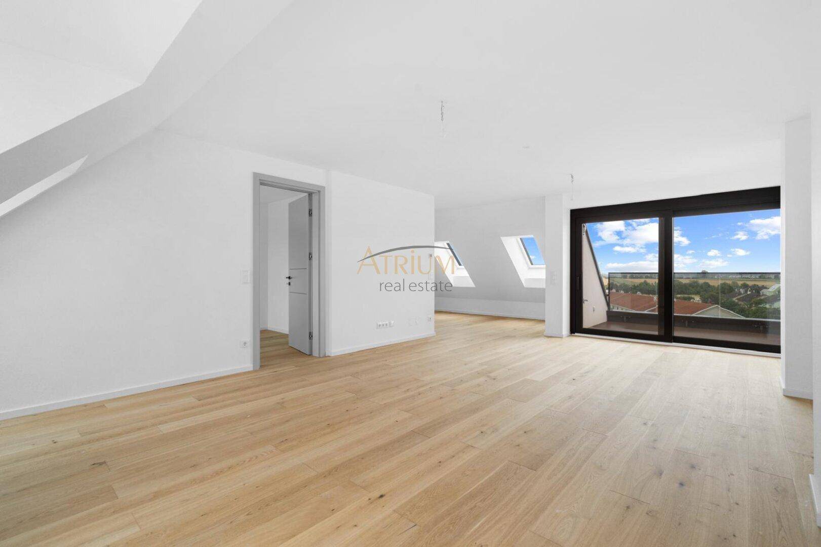 Geräumiger, heller Wohnbereich mit Holzboden, Dachschrägen und Zugang zum Balkon.