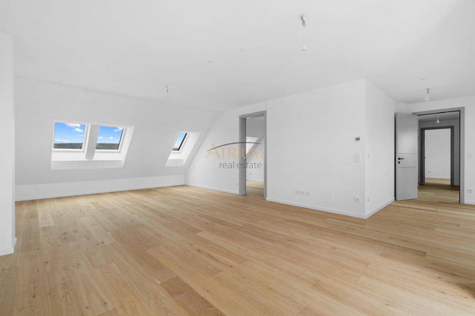 Heller Wohnraum mit Holzboden, Dachschrägen und mehreren Dachfenstern für viel Tageslicht.