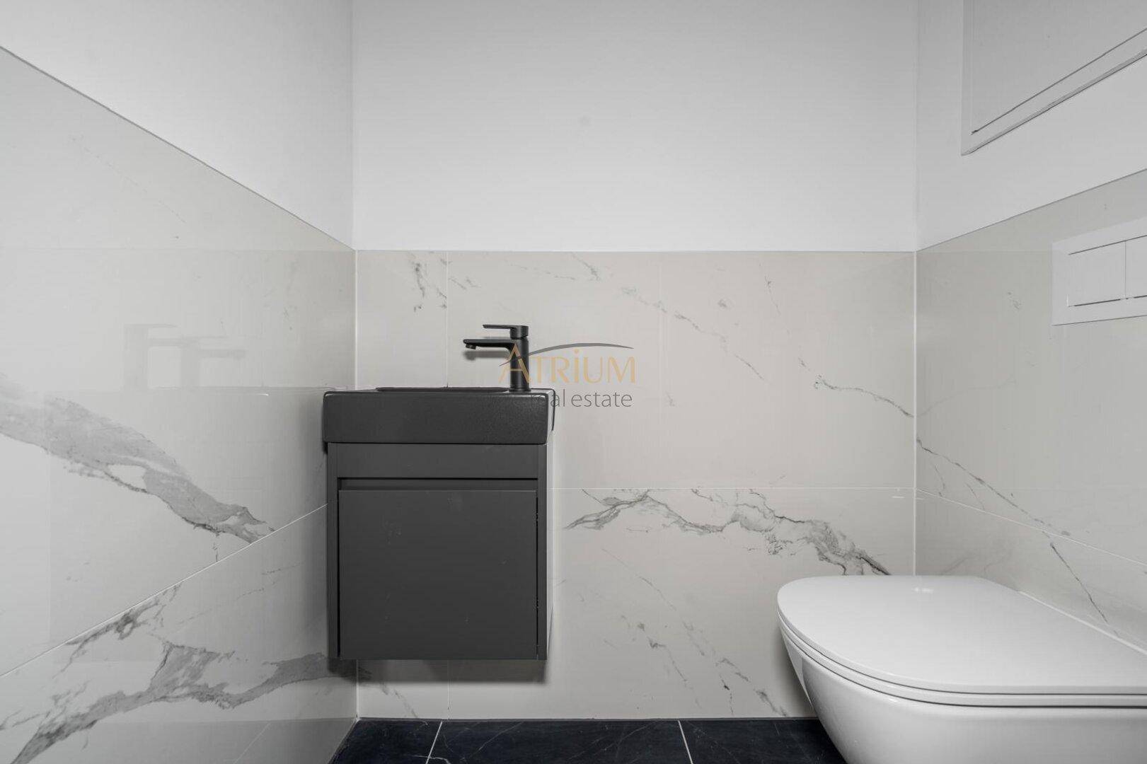 Modernes Gäste-WC mit Marmoroptik-Fliesen, wandhängendem WC und stilvollem Waschtisch.