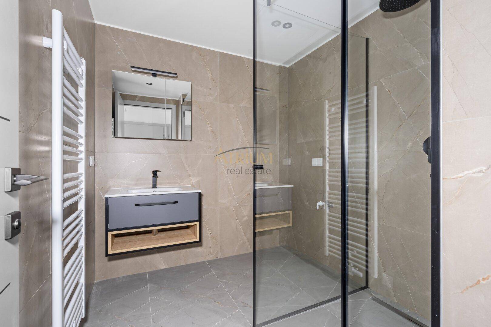 Modernes Badezimmer mit begehbarer Dusche, beheiztem Handtuchhalter und eleganten Fliesen.