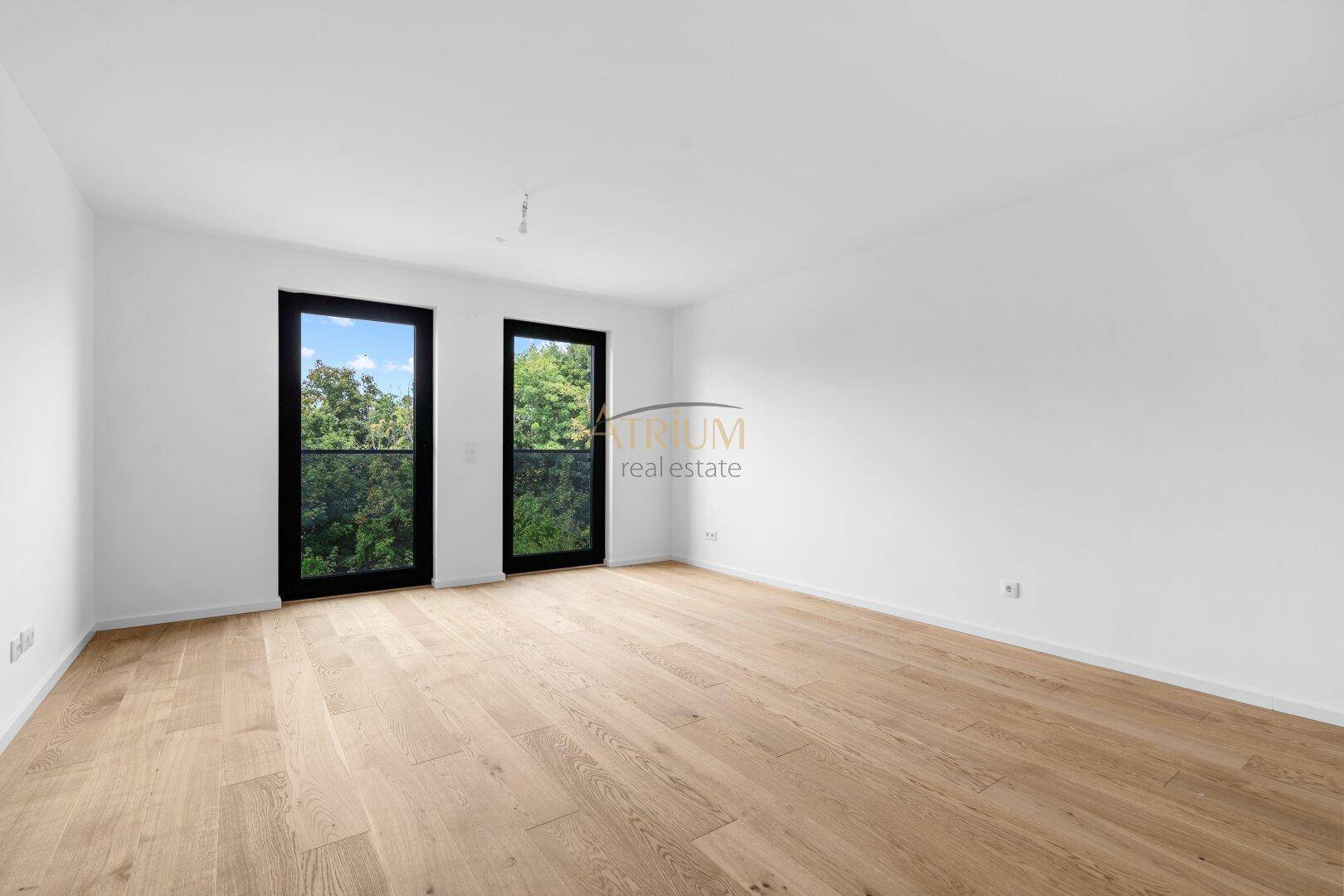 Geräumiges, helles Zimmer mit Parkettboden und zwei französischen Balkonen mit Blick ins Grüne.