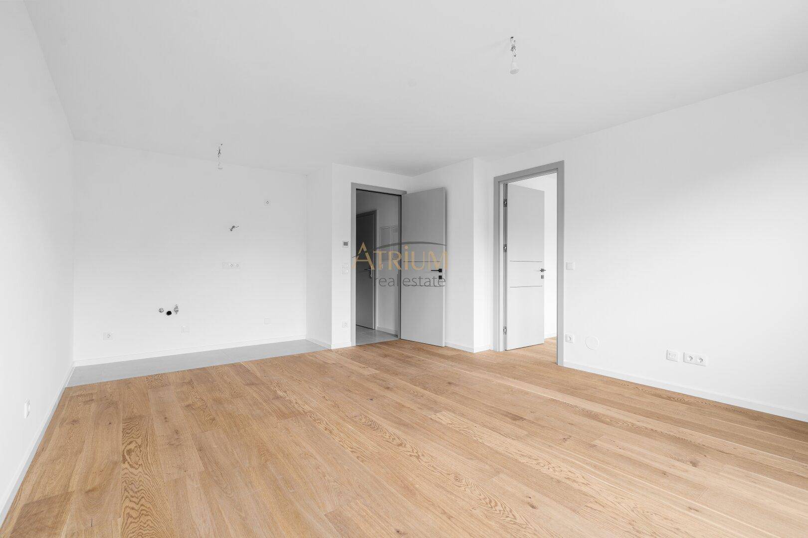 Leeres Zimmer mit hellem Holzboden und weißen Wänden, bereit für die individuelle Gestaltung.