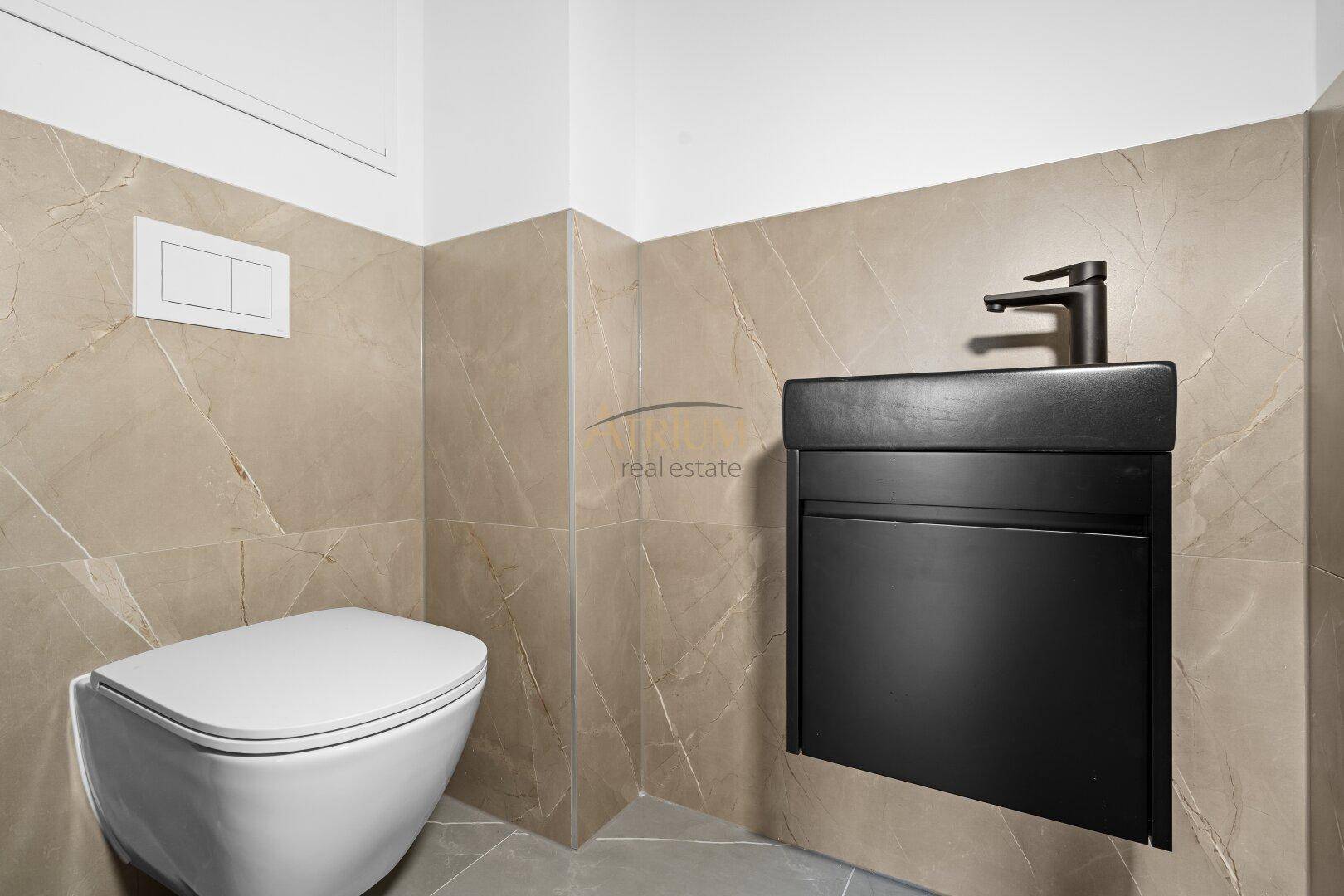 Modernes Gäste-WC mit beigefarbenen Fliesen, wandhängendem WC und schwarzem Waschbecken.