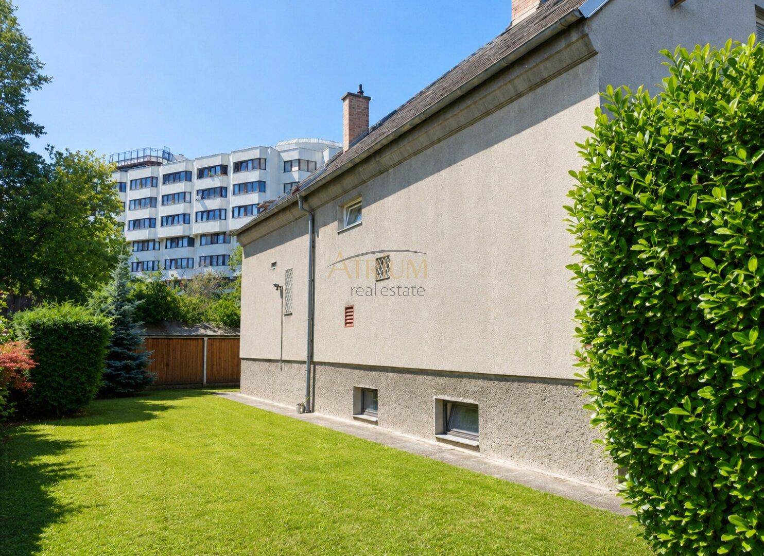 Gepflegter Rasenbereich neben dem Haus mit Blick auf moderne Gebäude im Hintergrund.