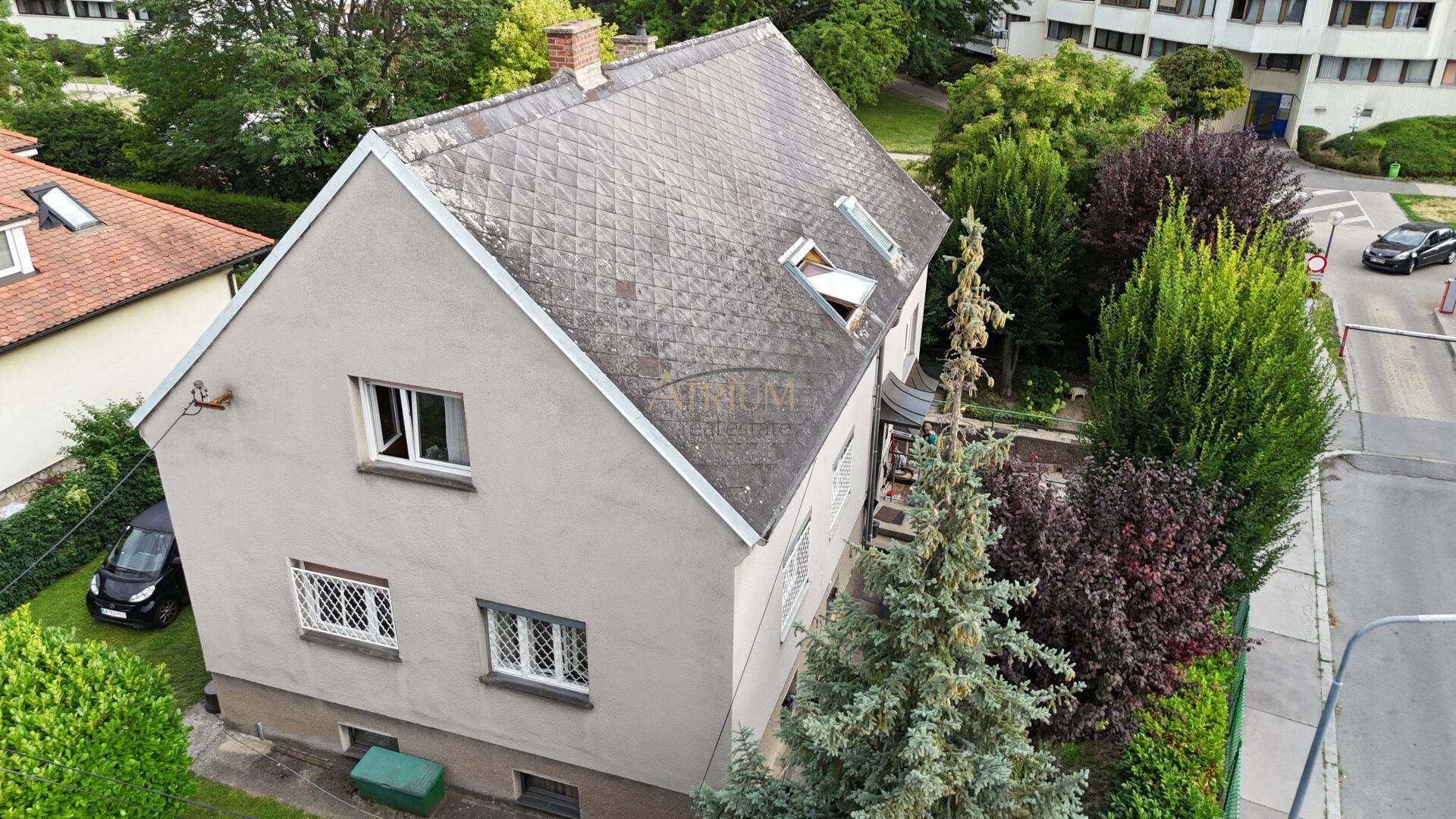 Luftaufnahme eines Einfamilienhauses mit Satteldach und umliegender Grünfläche.